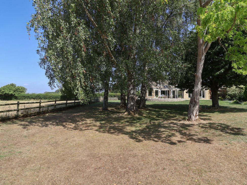An outdoor area with trees and grass at Leafield Cottage in Brockworth