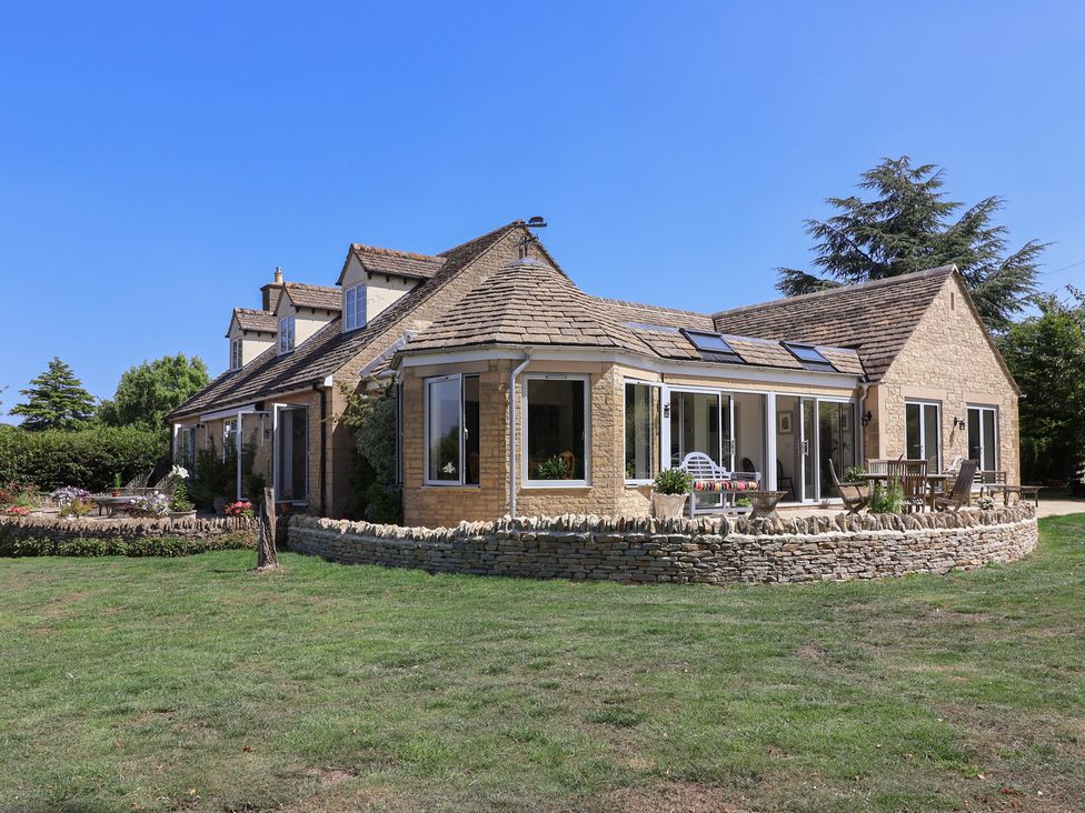 A house with a garden and stone wall at Leafield Cottage in Brockworth