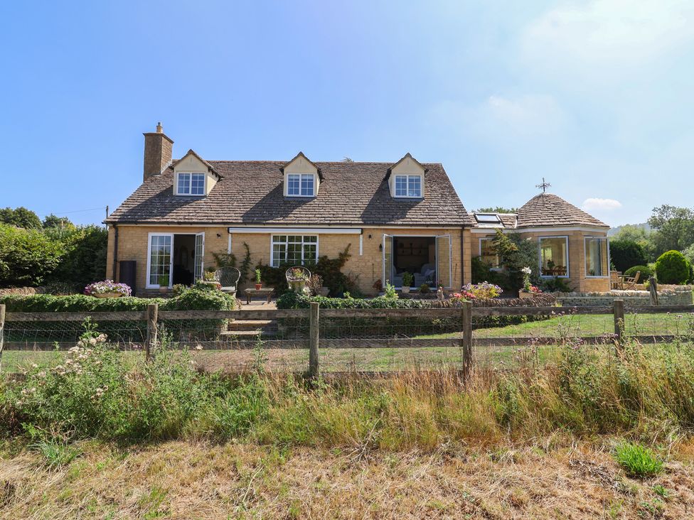 A house with garden and seating area at Leafield Cottage in Brockworth