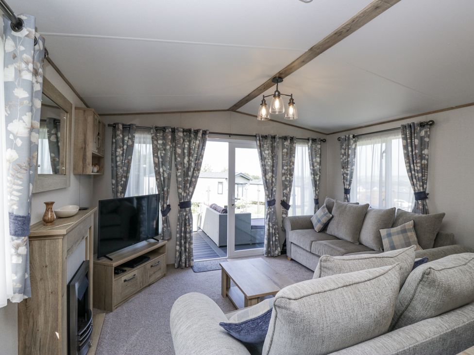 A living room featuring a sofa, television, and coffee table at Grasmoor View Lodge