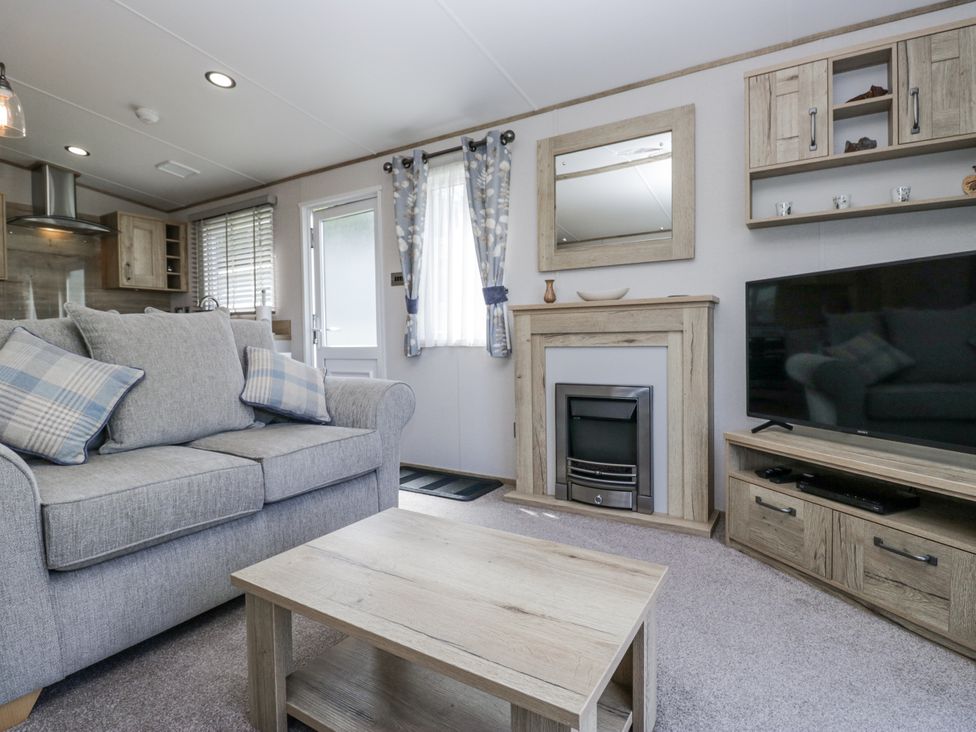A living room with a sofa and television at Grasmoor View Lodge