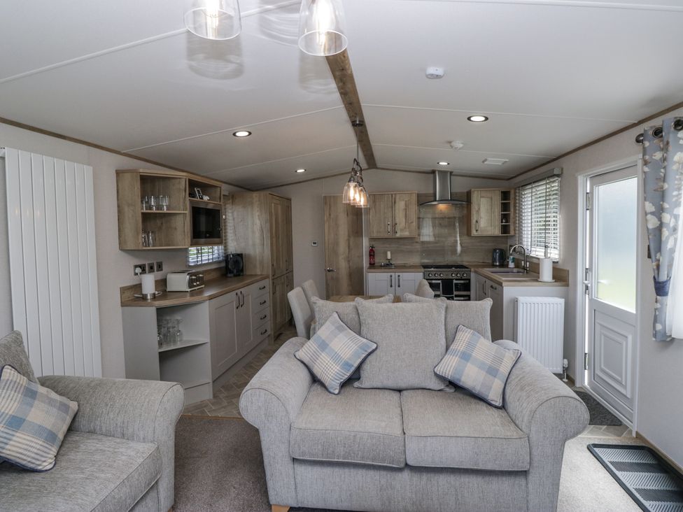 A living room with a sofa and kitchen area at Grasmoor View Lodge