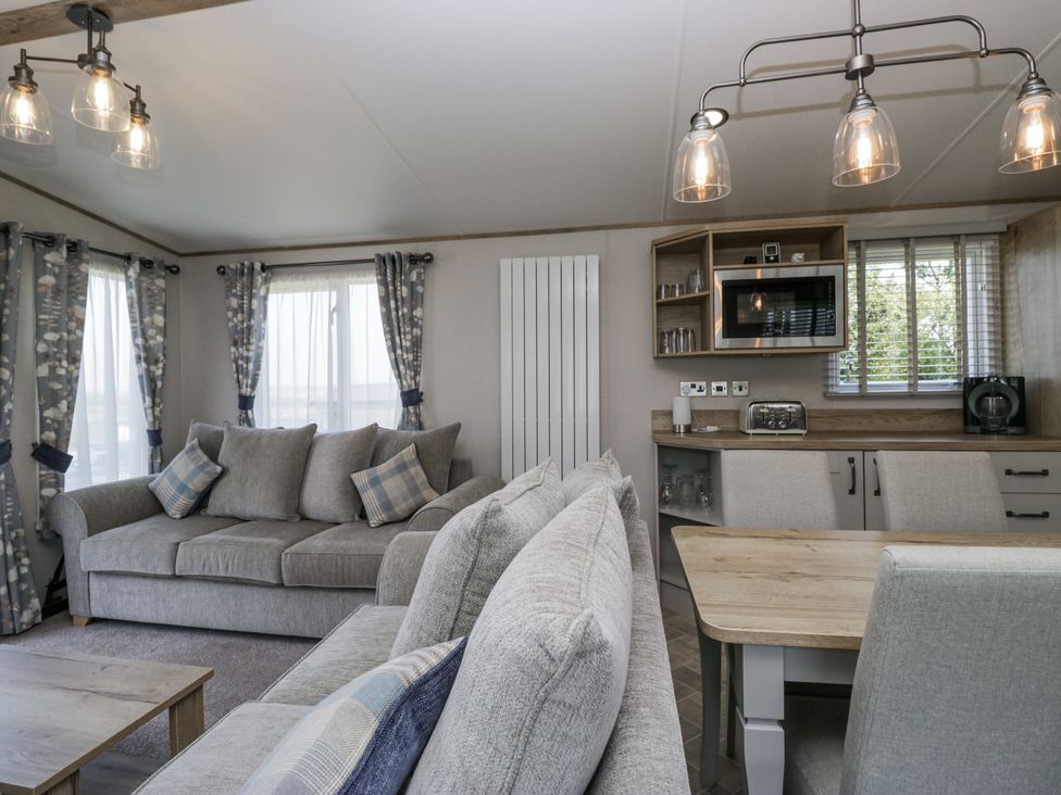 A living room with sofas and a dining area at Grasmoor View Lodge