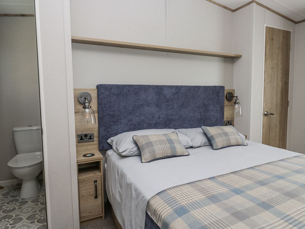 A bedroom with a bed and bedside table at Grasmoor View Lodge