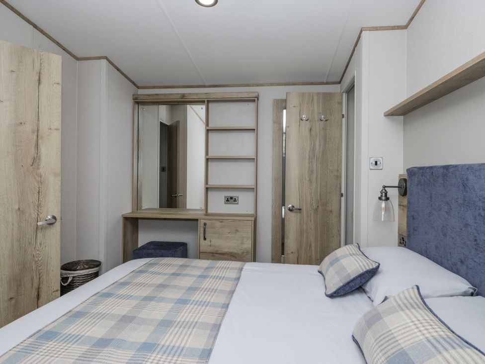 A bedroom with a bed and dressing table at Grasmoor View Lodge