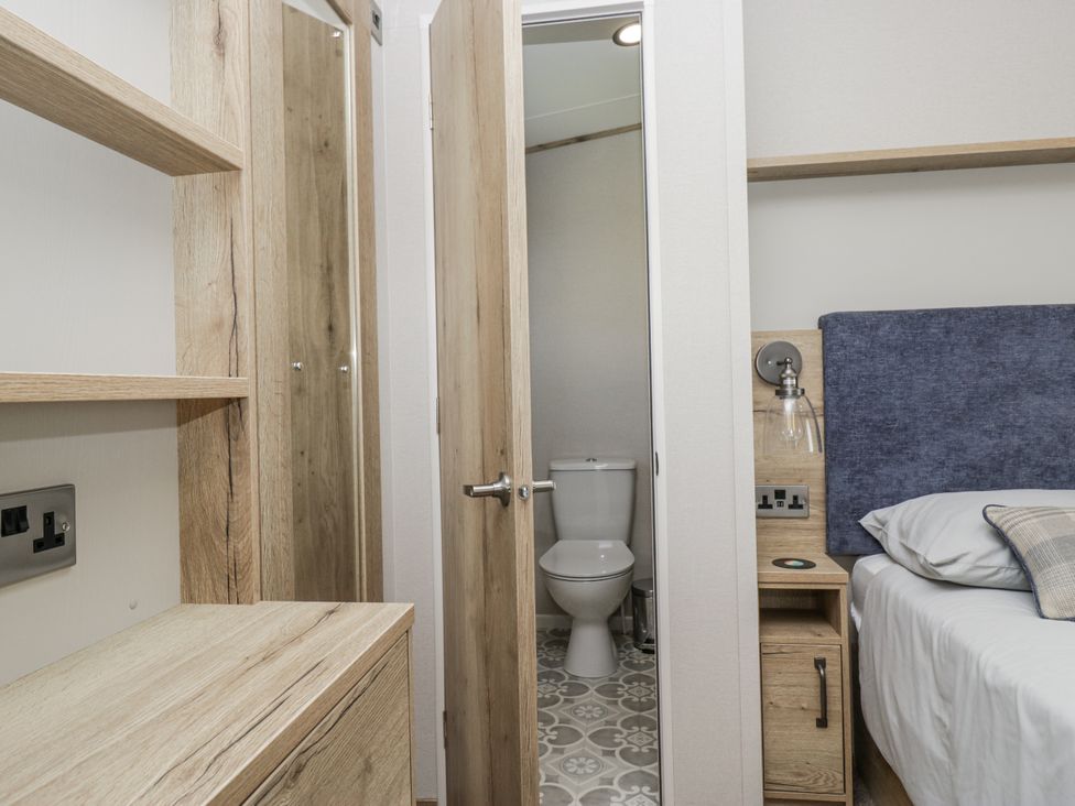 A bedroom with a toilet visible through an open door at Grasmoor View Lodge