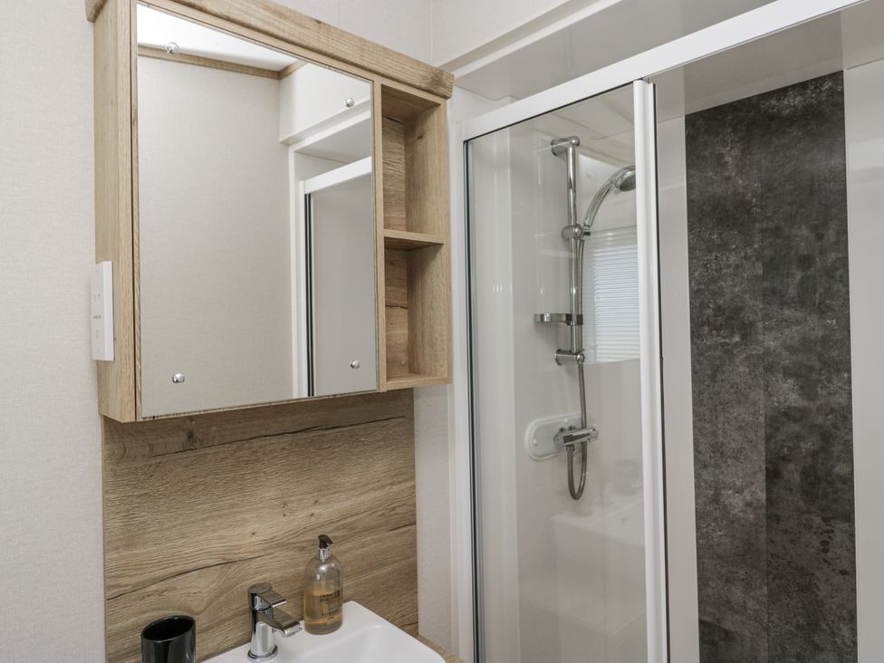 A bathroom with a mirror, sink, and shower at Grasmoor View Lodge
