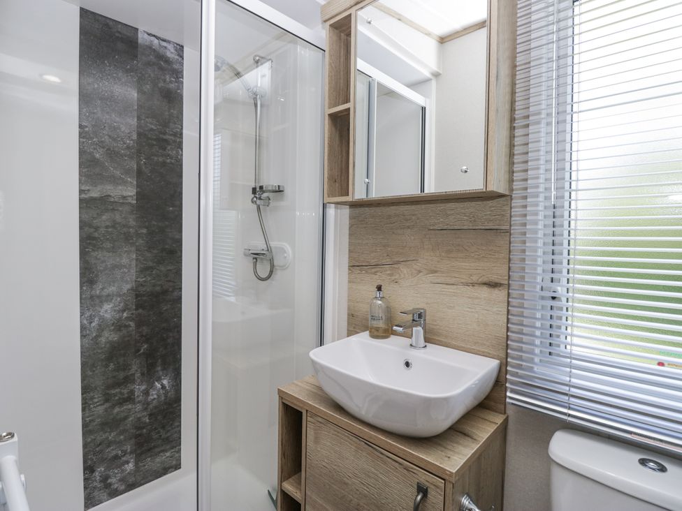 A bathroom with a shower, sink, and cabinet at Grasmoor View Lodge