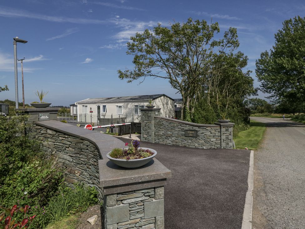 An outdoor entrance with a stone wall and caravan at Grasmoor View Lodge