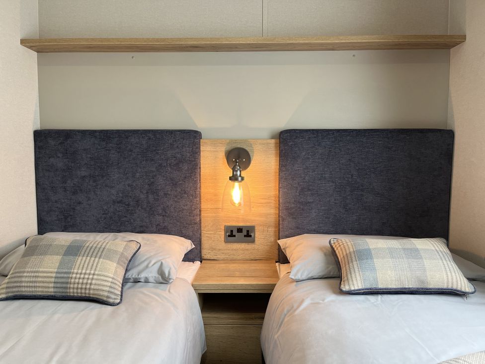 A bedroom with two beds and bedside table at Winscales Rest in Winscales