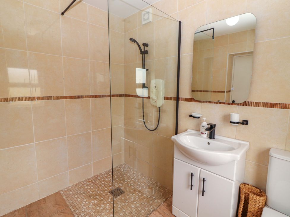 A bathroom with a shower, sink, and toilet at The Farmhouse in Tralee, County Kerry