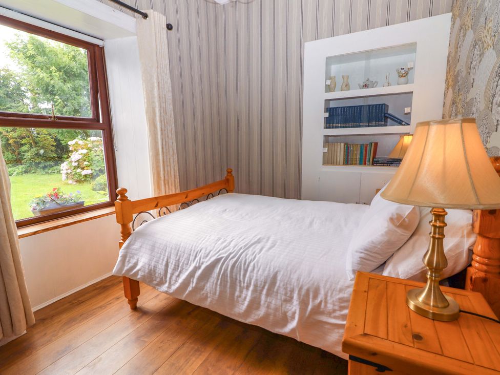A bedroom with a bed and a bookshelf at The Farmhouse in Tralee, County Kerry