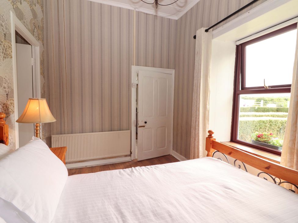 A bedroom with a bed and window at The Farmhouse in Tralee, County Kerry