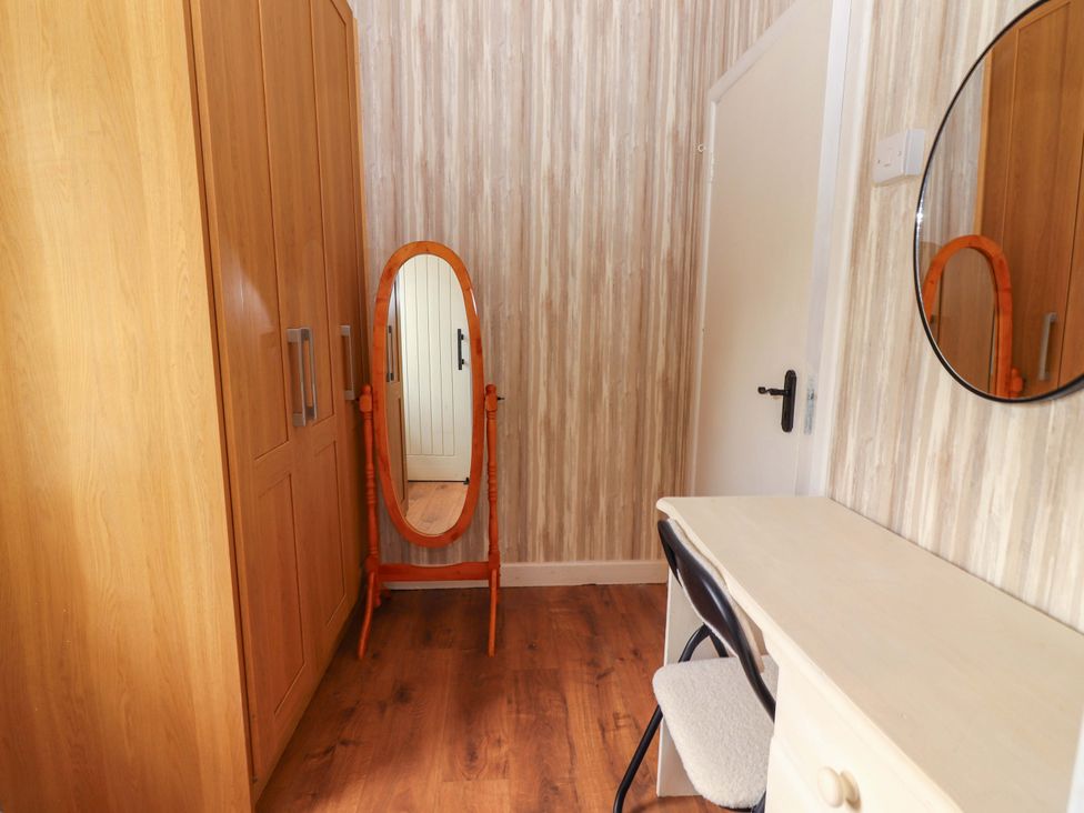 A bedroom with a wardrobe, mirror, chair, and table at The Farmhouse in Tralee, County Kerry