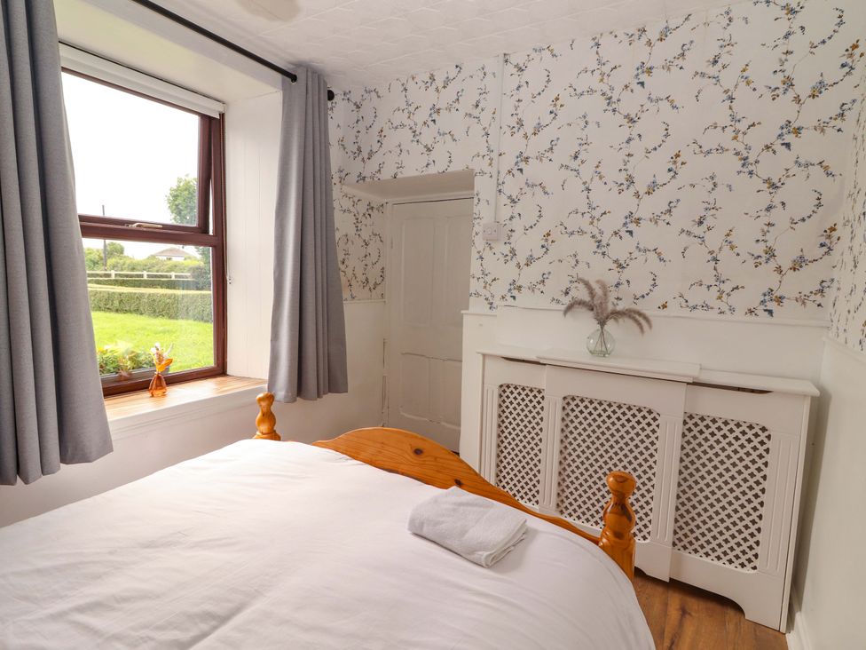 A bedroom with a bed and window at The Farmhouse in Tralee, County Kerry