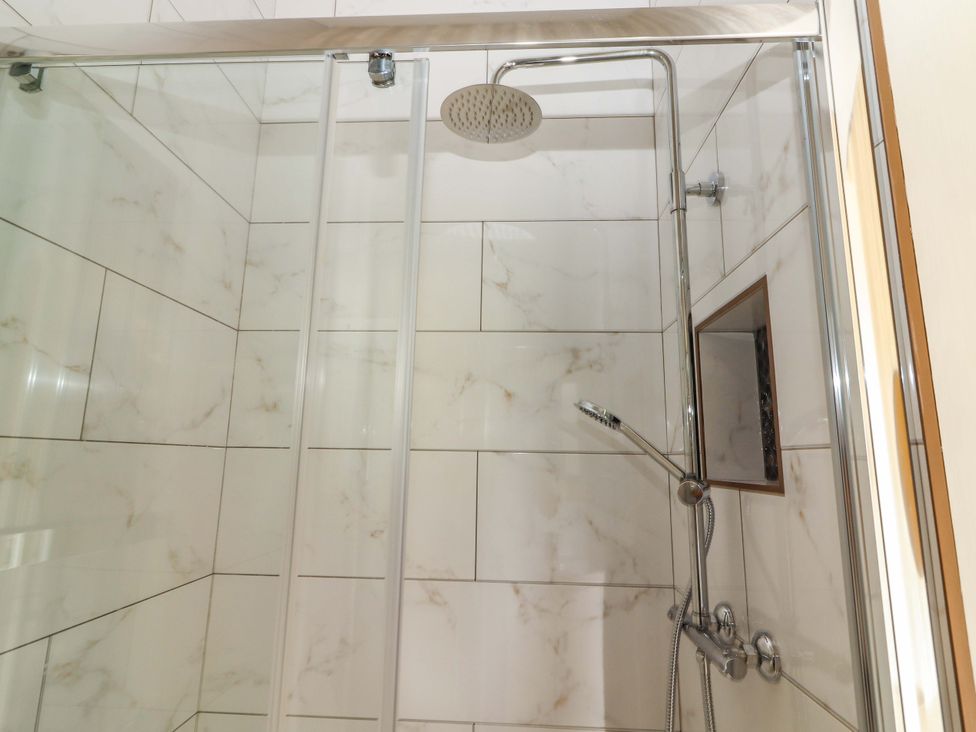A shower with tiles and fixtures at The Farmhouse in Tralee, County Kerry