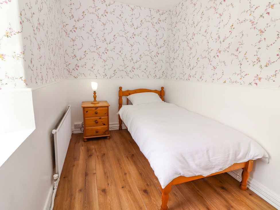 A bedroom with a single bed and nightstand at The Farmhouse in Tralee, County Kerry