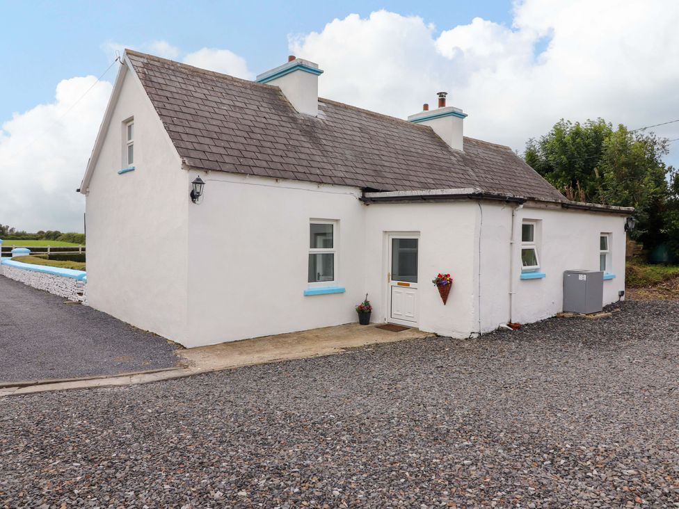 A cottage with a door and windows on a gravel driveway at The Farmhouse in Tralee, County Kerry