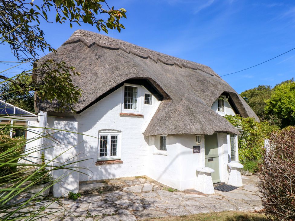 A cottage with a thatched roof and a stone path at Smugglers Cottage in New Milton