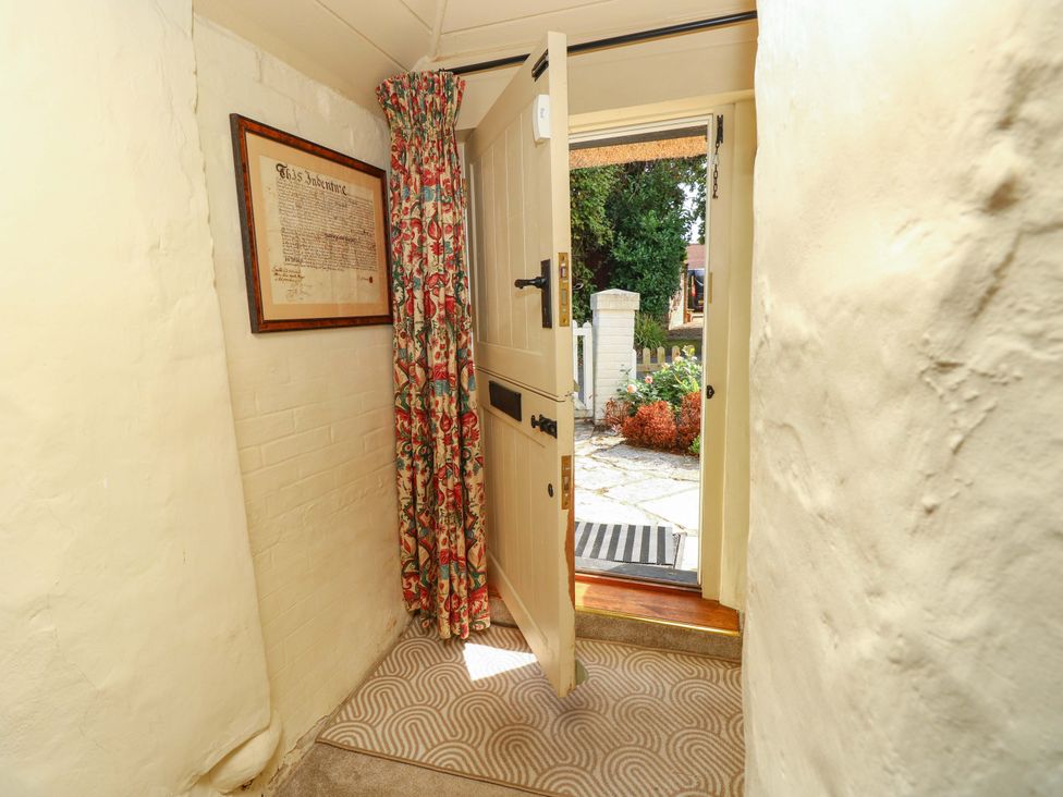 A hallway with an open door and a curtain at Smugglers Cottage in New Milton