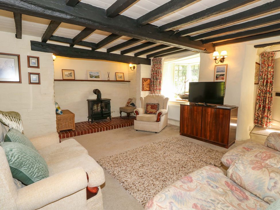 A living room with a fireplace and television at Smugglers Cottage in New Milton