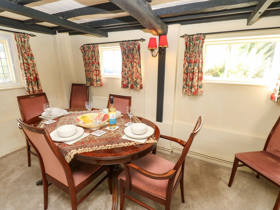 A dining room with a table set for meals at Smugglers Cottage in New Milton