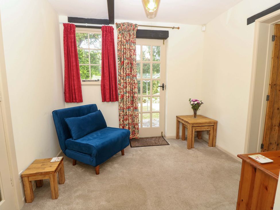 A living room with an armchair and a wooden table at Smugglers Cottage in New Milton