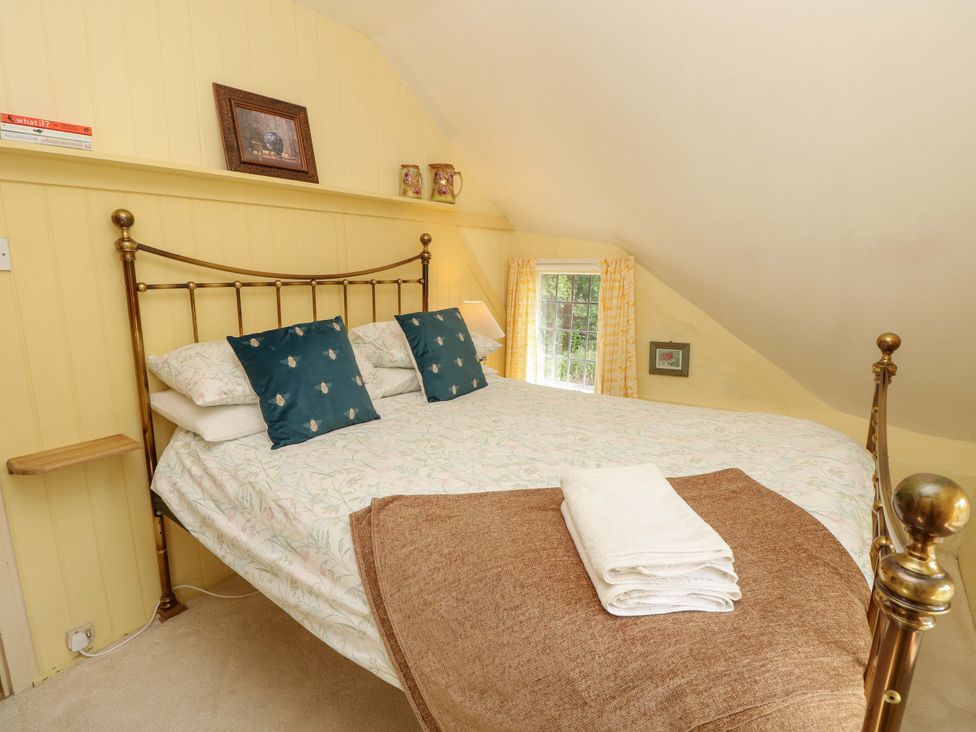 A bedroom with a bed and shelves at Smugglers Cottage in New Milton