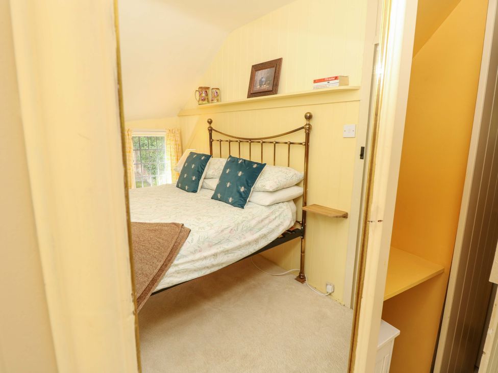 A bedroom with a bed and window at Smugglers Cottage in New Milton