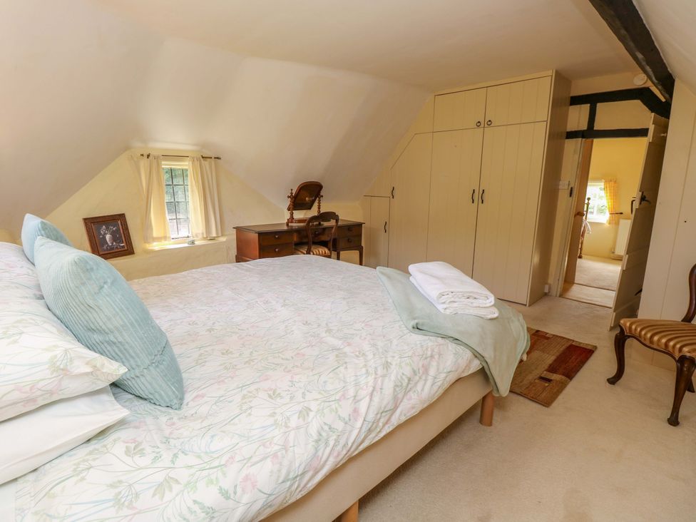 A bedroom with a bed and desk in Smugglers Cottage New Milton