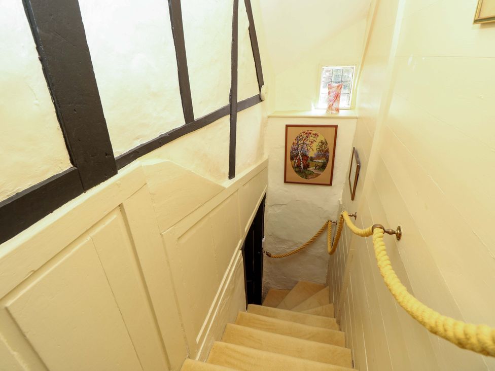 A staircase with a handrail and framed artwork at Smugglers Cottage in New Milton