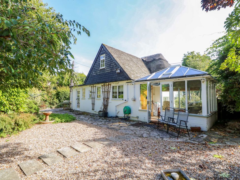 A garden with a house and a conservatory at Smugglers Cottage in New Milton