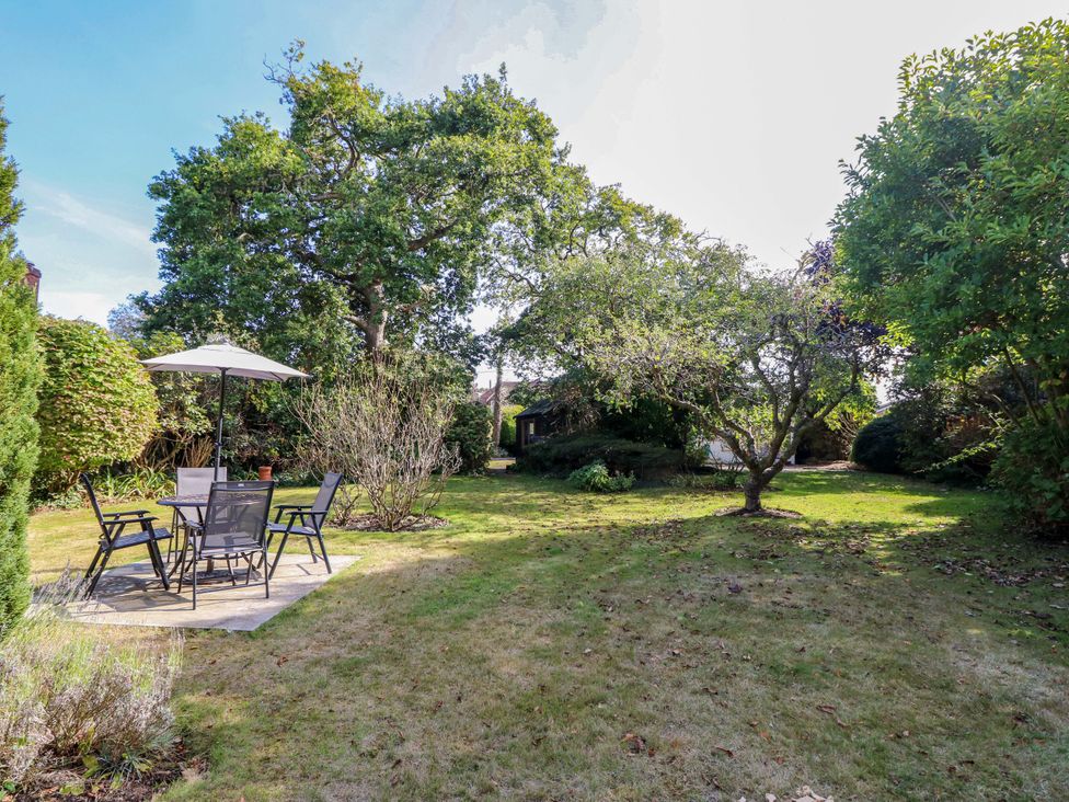 A garden with a table, chairs, and trees at Smugglers Cottage in New Milton