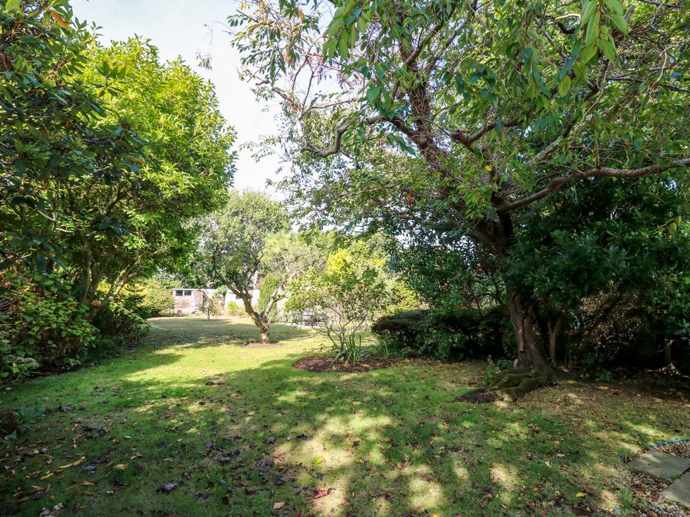 A garden with trees and grass at Smugglers Cottage in New Milton