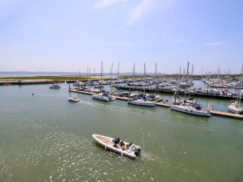 A marina with boats docked and a small boat on the water at Smugglers Cottage in New Milton
