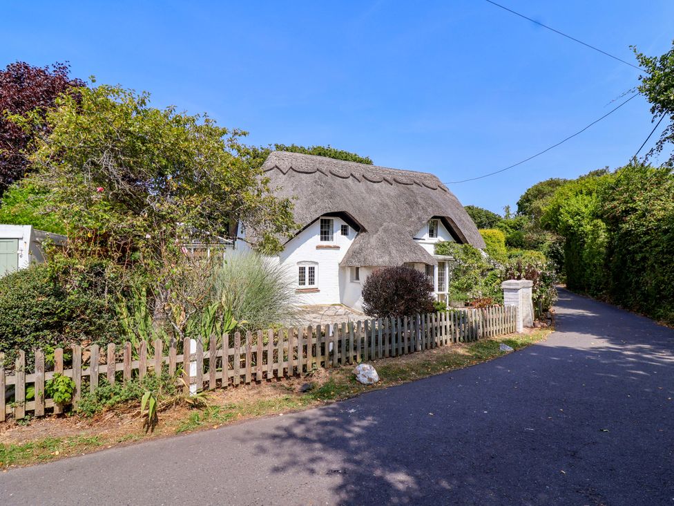 A thatched roof cottage with a garden at Smugglers Cottage Barton On Sea
