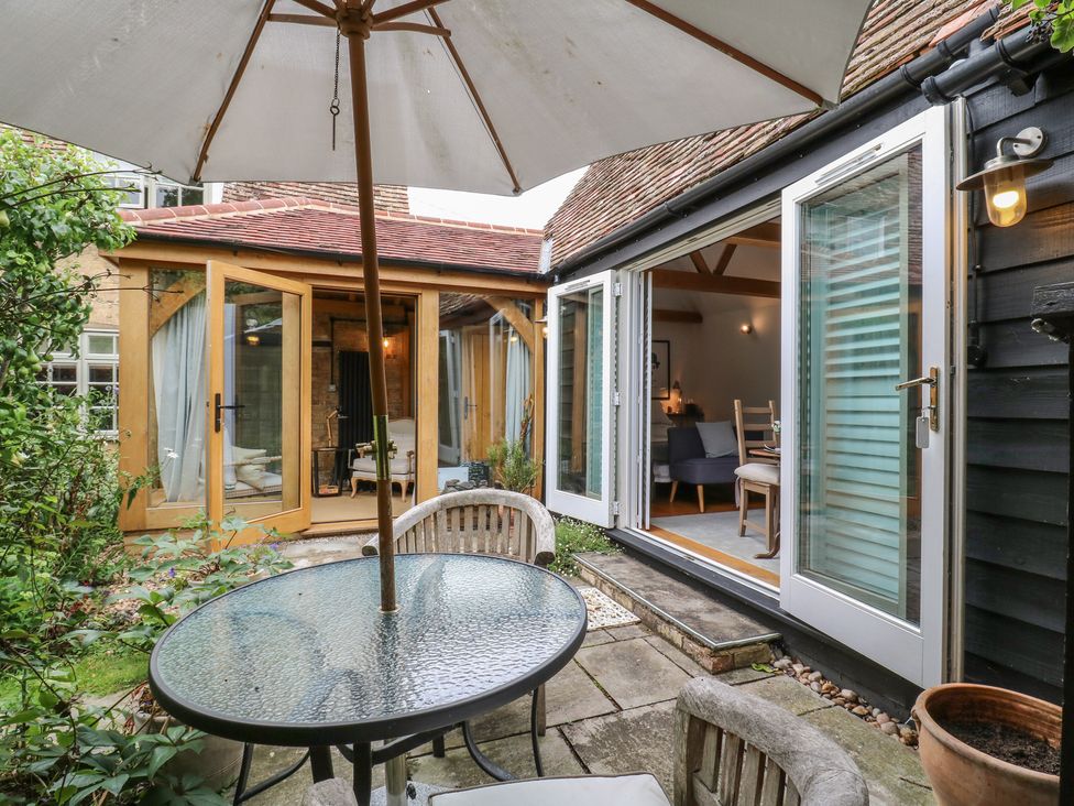 An outdoor area with a table and umbrella near an open entrance at Little Barn @ Orwell
