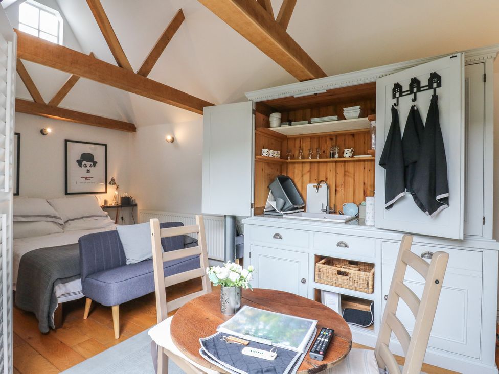 A studio with a bed, sofa, table, and kitchenette at Little Barn @ Orwell
