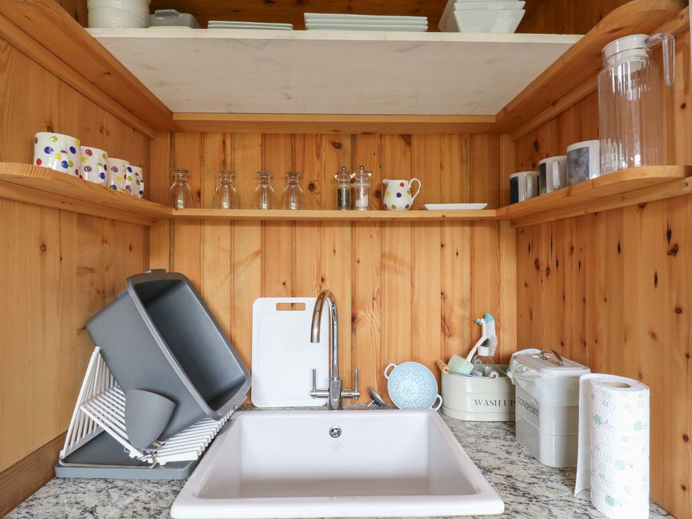 A kitchen sink with dishes and storage containers at Little Barn @ Orwell