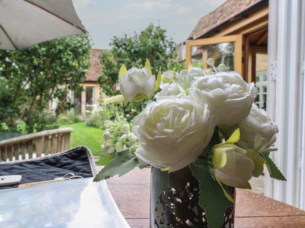 A table with flowers in a vase overlooking the garden at Little Barn @ Orwell