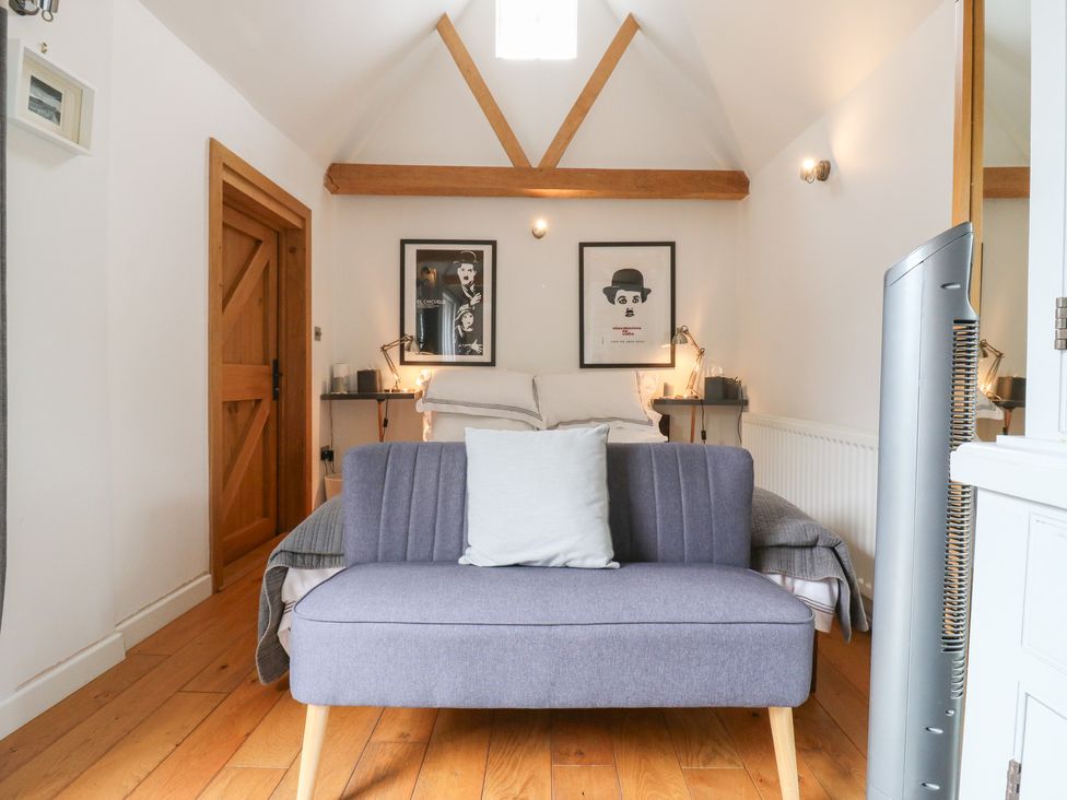 A bedroom with a bed, sofa, and framed artwork at Little Barn @ Orwell
