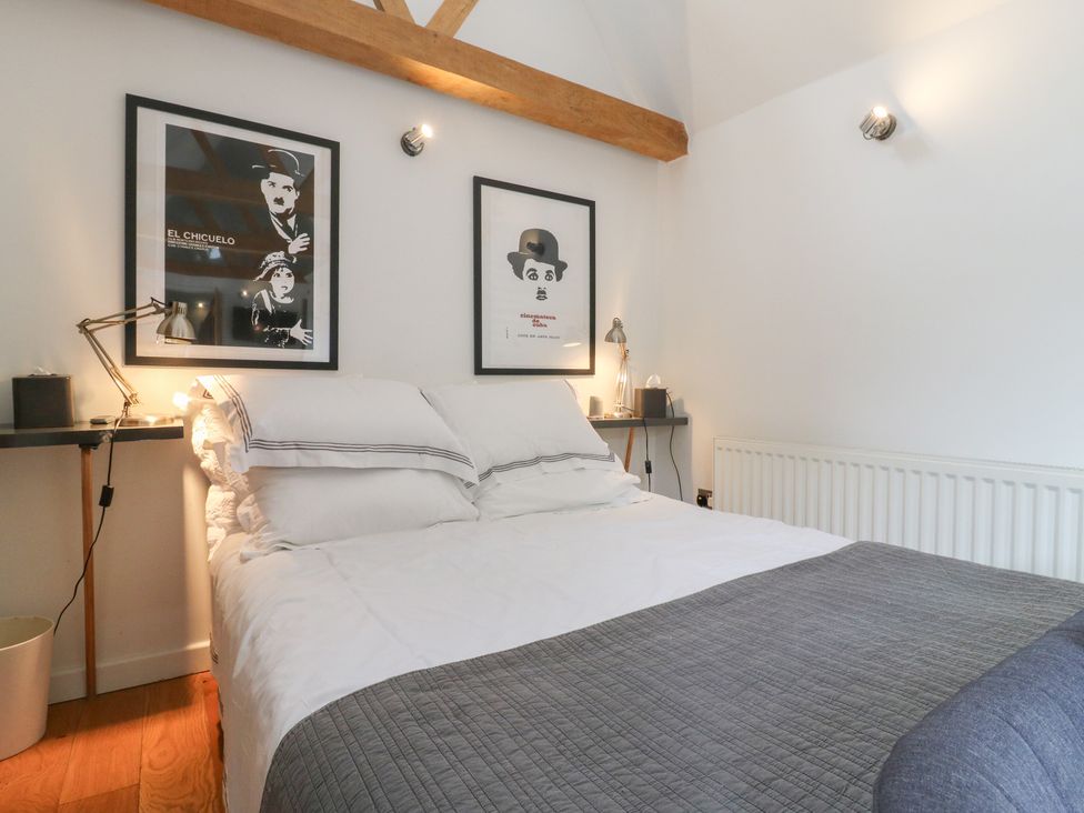 A bedroom with a bed, bedside tables, and posters at Little Barn @ Orwell