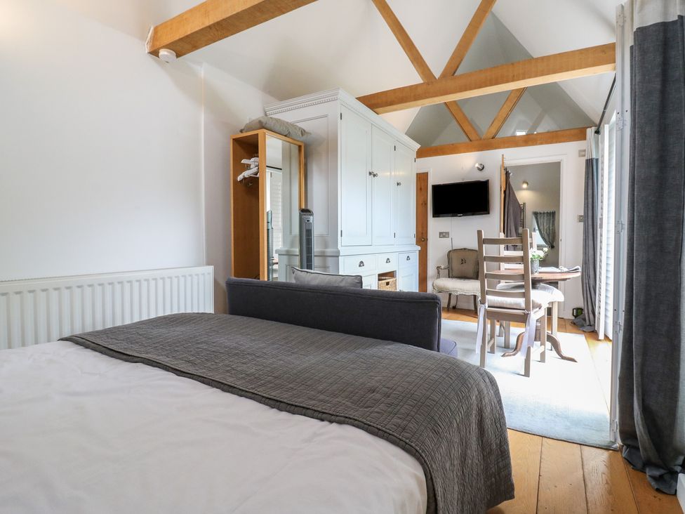 A bedroom with a bed, wardrobe, table, and chairs at Little Barn @ Orwell