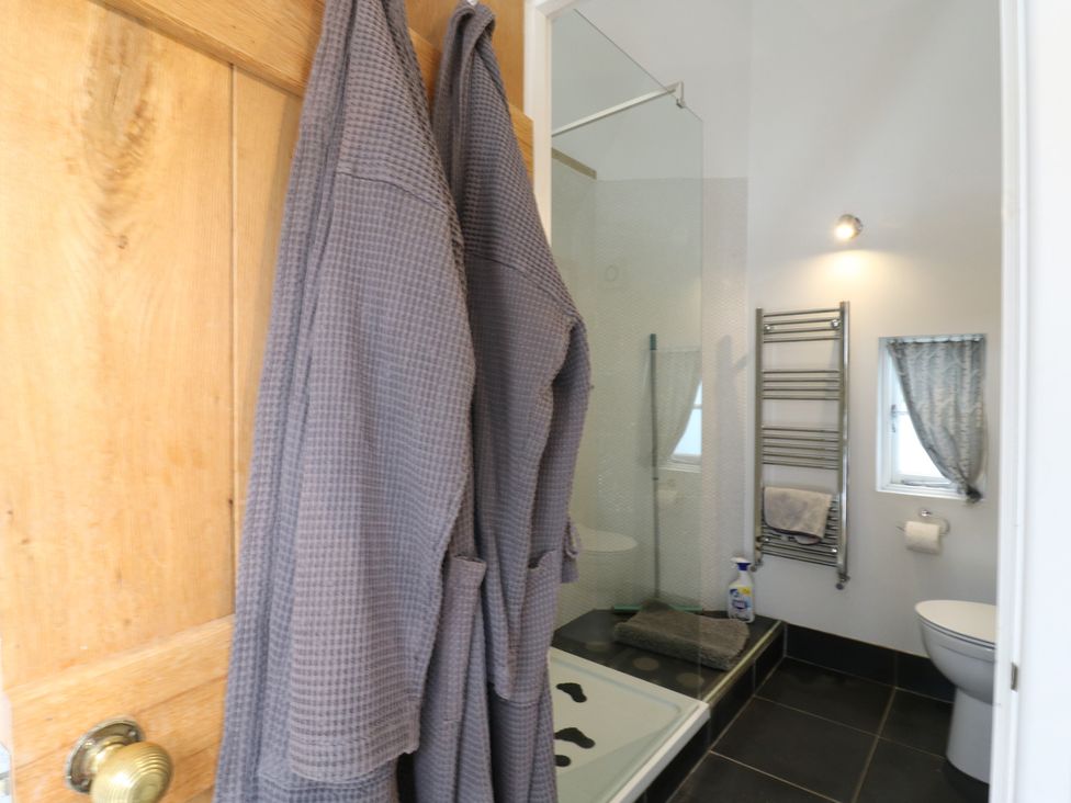 A bathroom with a shower, towels, and a toilet at Little Barn @ Orwell