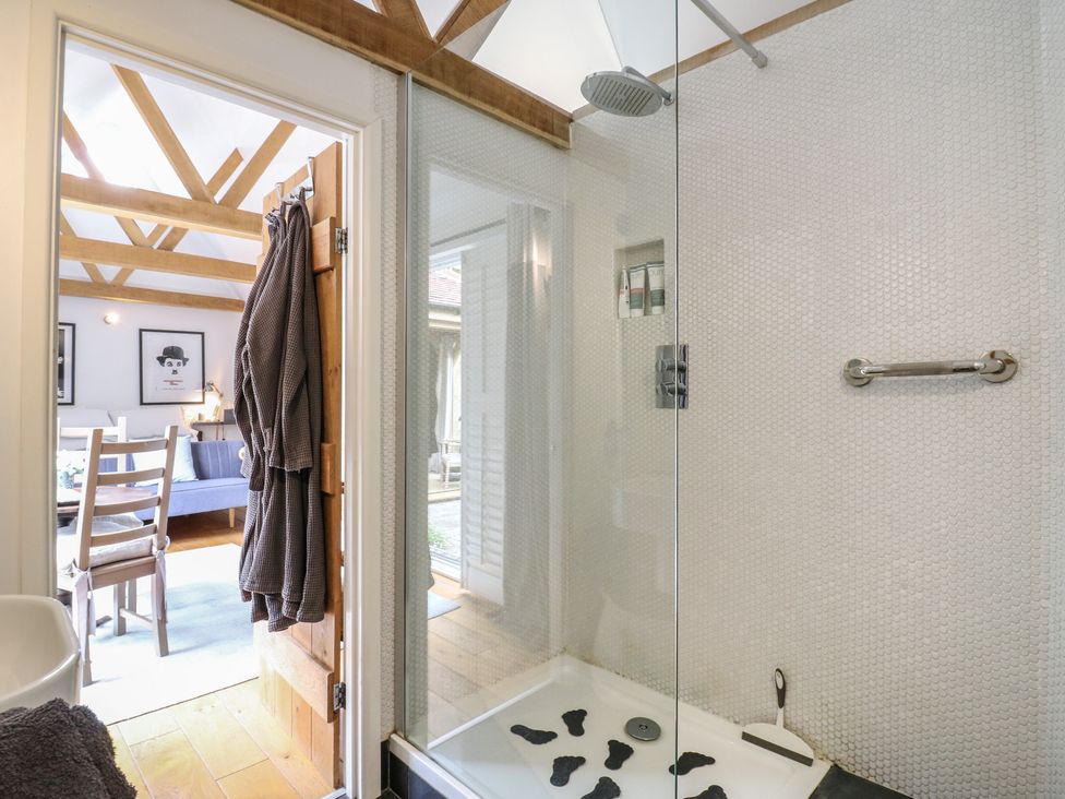 A bathroom with a shower, towel rack, and wooden beams at Little Barn @ Orwell