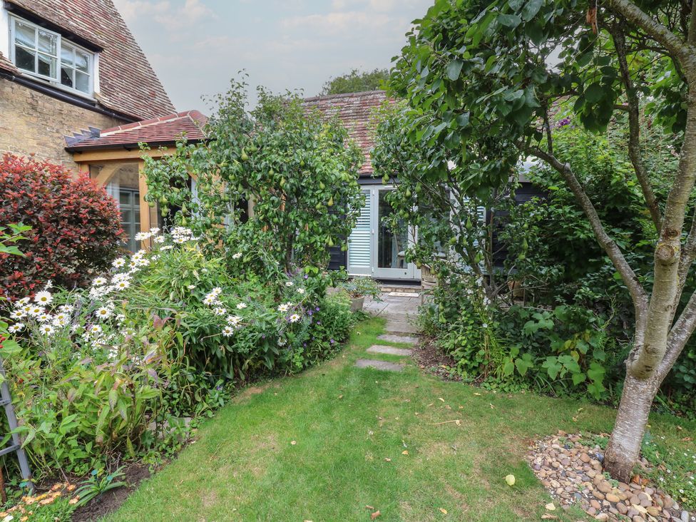 A garden with flowers and a pathway leading to a door at Little Barn @ Orwell