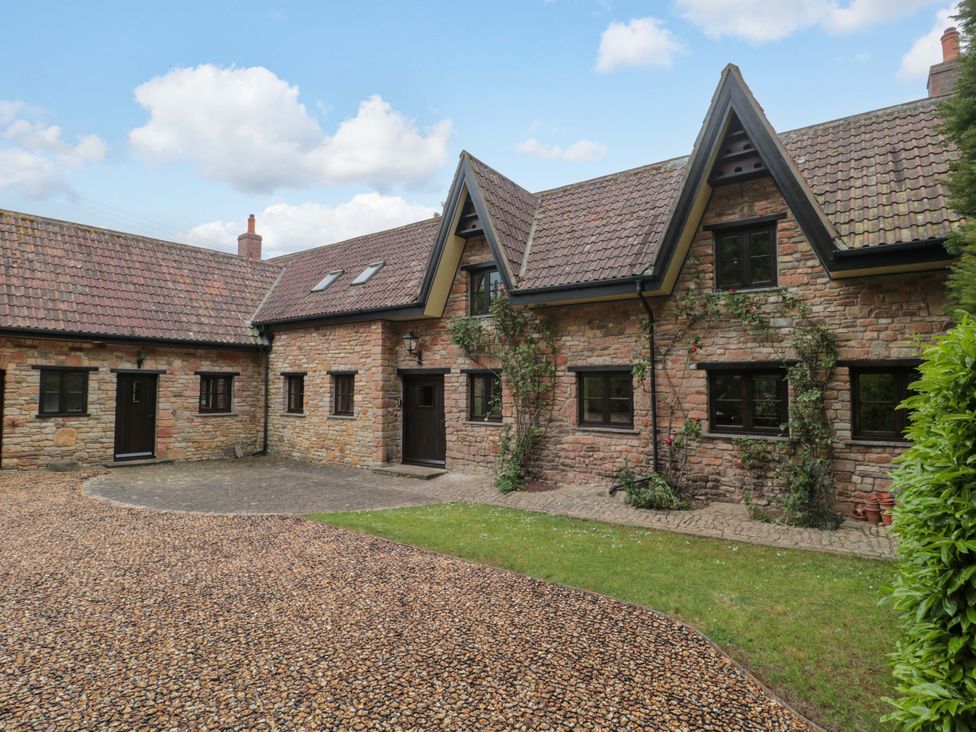 A house with stone exterior and gravel driveway at Stowey Mead Stables in Bishop Sutton