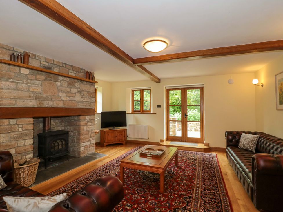A living room with a fireplace and television at Stowey Mead Stables in Bishop Sutton