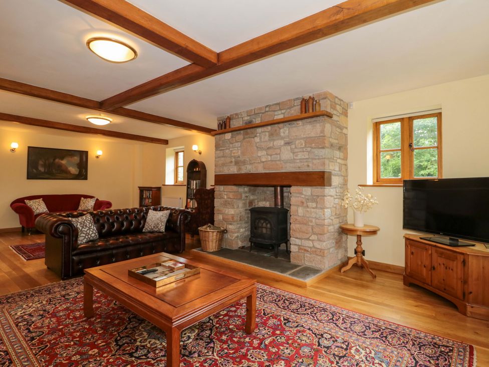 A living room with a fireplace and television at Stowey Mead Stables in Bishop Sutton