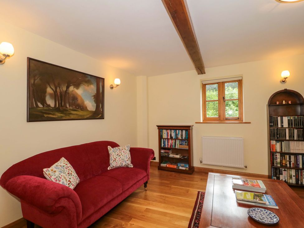 A living room with a sofa and bookshelf at Stowey Mead Stables in Bishop Sutton